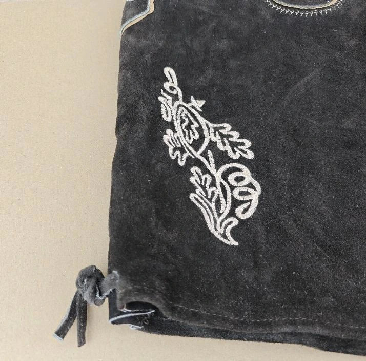 Black fabric with white embroidered design on a beige background
