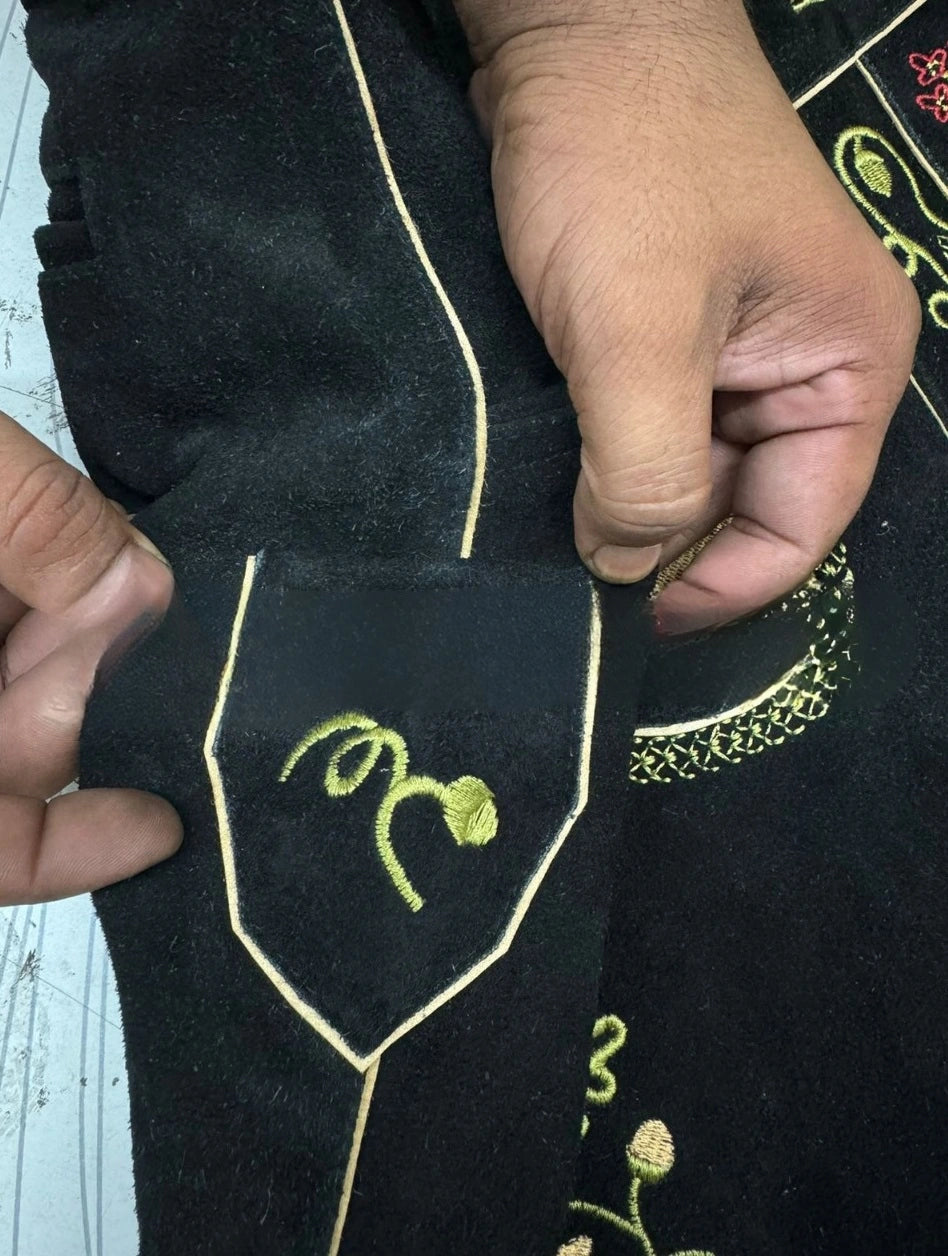 Embroidered fabric with green floral design held by a hand