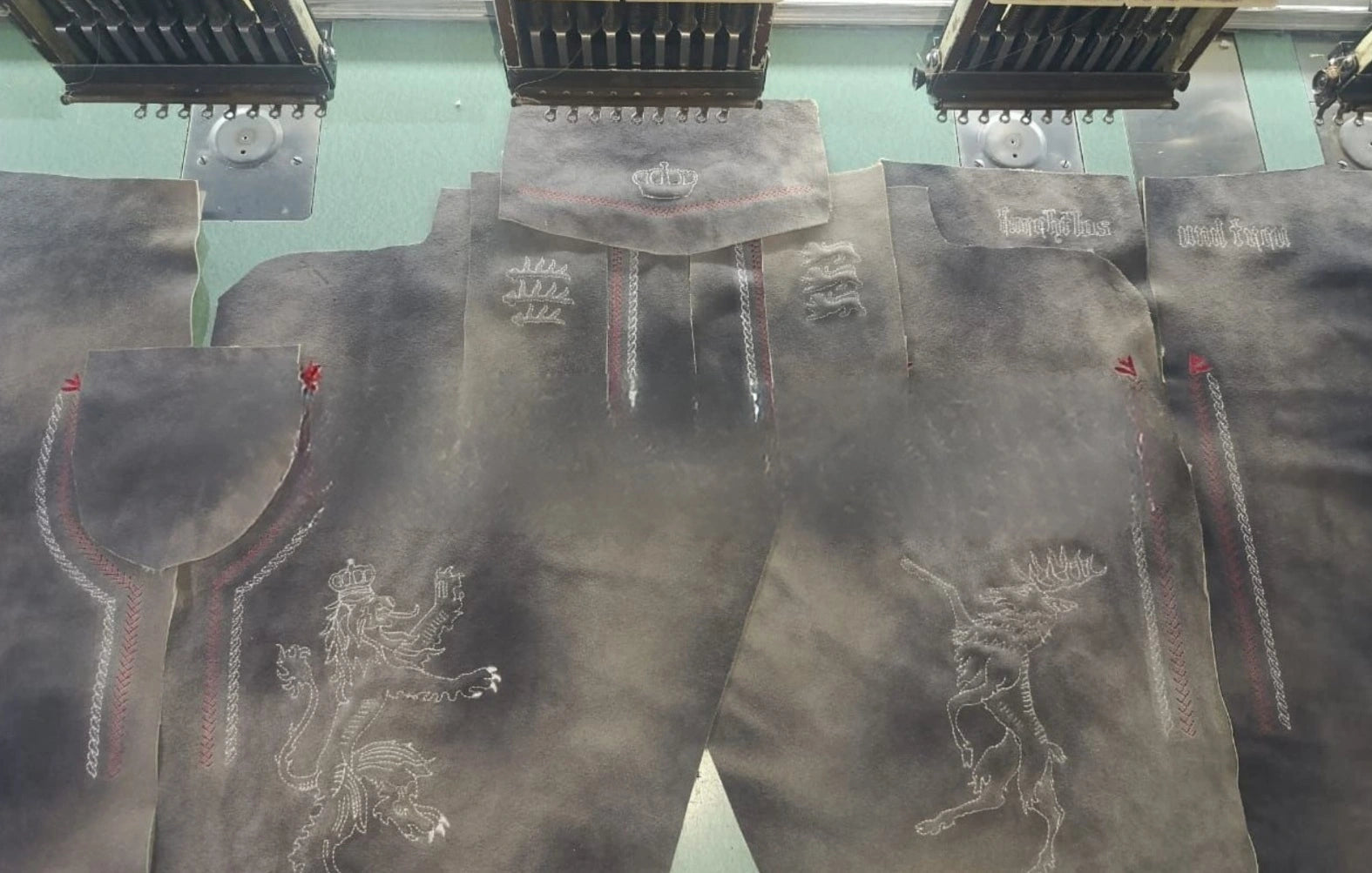 Multiple pairs of dark jeans with brand logos on a green surface