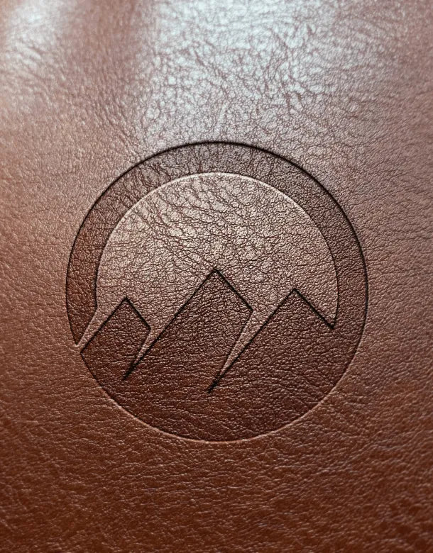 Close-up of a brown leather surface with an embossed logo.