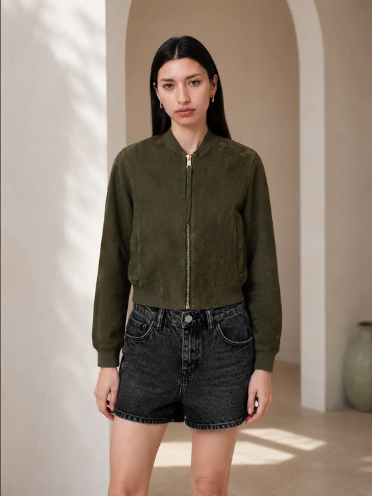 Woman wearing a green jacket and black shorts in a sunlit room.