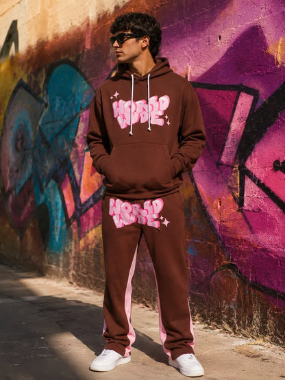Person wearing a brown tracksuit with pink text in front of a graffiti wall.