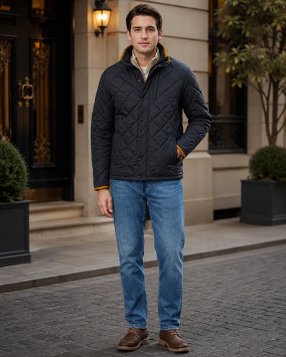 Man wearing a quilted jacket and blue jeans standing on a street.