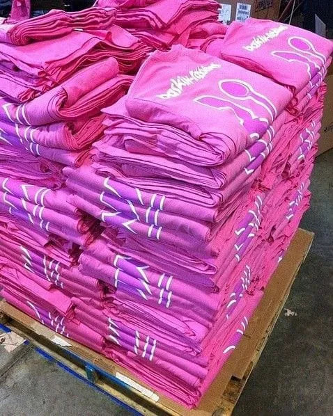 Stack of pink t-shirts with logos on a pallet