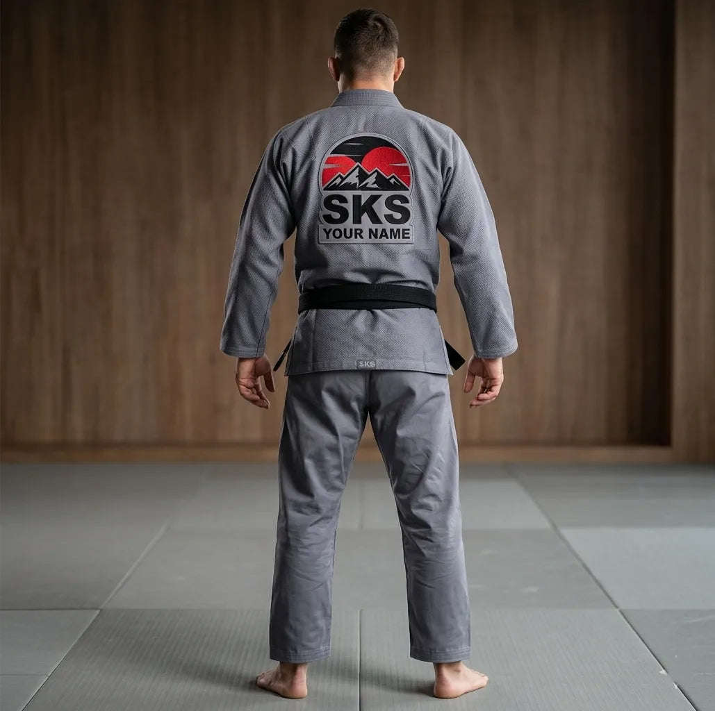 Person wearing a gray Jiu-Jitsu gi with SKS branding in a dojo.