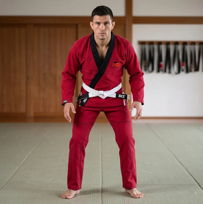 Man in red martial arts uniform with white belt standing in a dojo.
