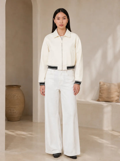 Person wearing a white outfit with black accents in a neutral setting